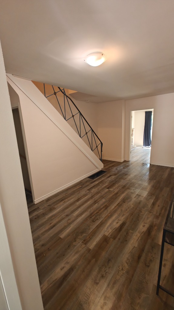 Finished staircase area with newly painted white walls and crisp black handrails